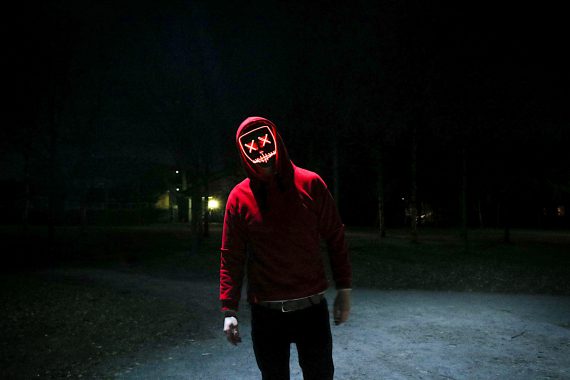 Das Foto zeigt einen Mann im roten Sweater beio Nacht. Statt dem Gesicht sieht man einen bösen Smiley. Das Foto bebildert die Folge 32 des Y Politik-Podcasts zur Frage, was man gegen den Hass tun kann.